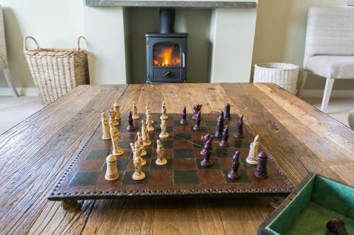 a chess game on a wooden table in front of a fireplace at Cae'r Borth in Moelfre