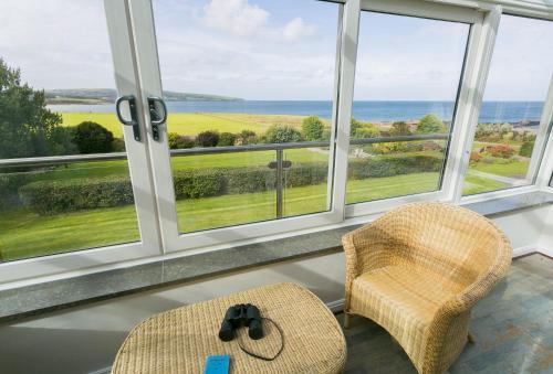 a room with two chairs and a view of the ocean at Cae'r Borth in Moelfre