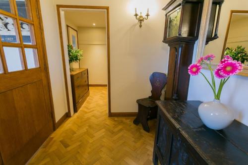 a hallway with a vase with flowers on a table at Cae'r Borth in Moelfre