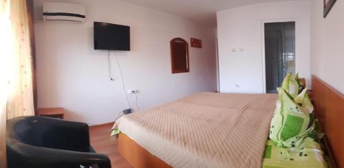 1 dormitorio con 1 cama, 1 silla y TV en Vila Efor, en Eforie Nord