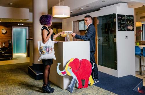 a man and a woman standing at a counter at Ibis Styles Wien City in Vienna