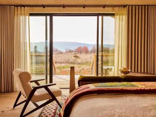 ein Schlafzimmer mit einem Bett, einem Stuhl und einem Fenster in der Unterkunft Wildflower Farms, Auberge Resorts Collection in Gardiner