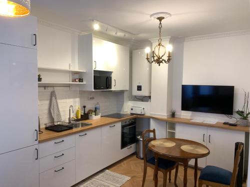 une cuisine avec des placards blancs, une table et une télévision dans l'établissement Apartment quartier St Louis - 10 mins walking Château Versailles, à Versailles