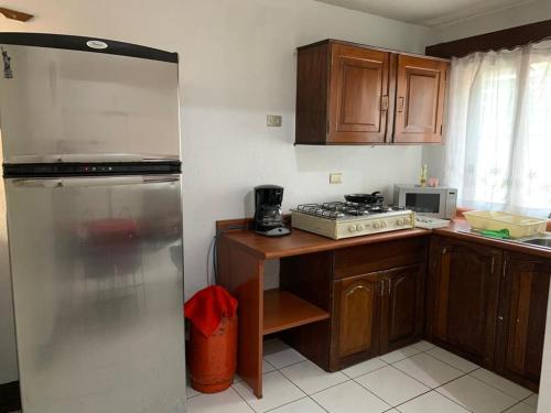 a kitchen with wooden cabinets and a stainless steel refrigerator at Casa a 5 minutos de los parques del IRTRA in Pucá