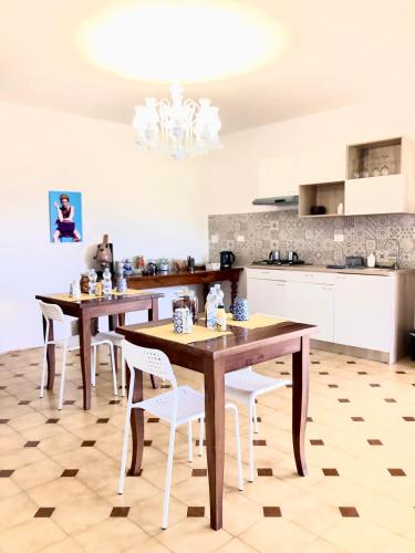 a kitchen with wooden tables and white chairs at B&B AcquaViva in Marina San Vito