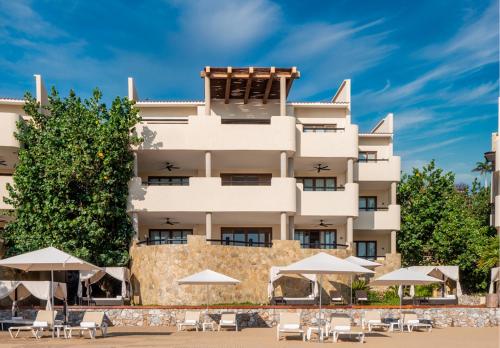 a hotel with tables and umbrellas in front of it at Celeste Beach Residences Huatulco Curamoria Collection in Santa Cruz Huatulco