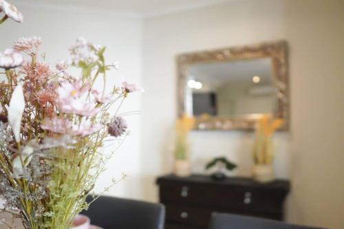 a vase of flowers on a table in front of a mirror at Top End Marvel -Darwin's Premier 3-BR Luxury Apt in Darwin