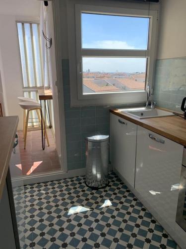 - une cuisine avec une poubelle sur un sol en damier dans l'établissement L'appart Fréjus plage, à Fréjus