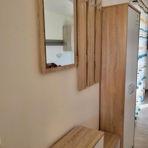 a bathroom with a mirror and a wooden cabinet at Apartmani Mia Sorajic in Petrovac na Moru