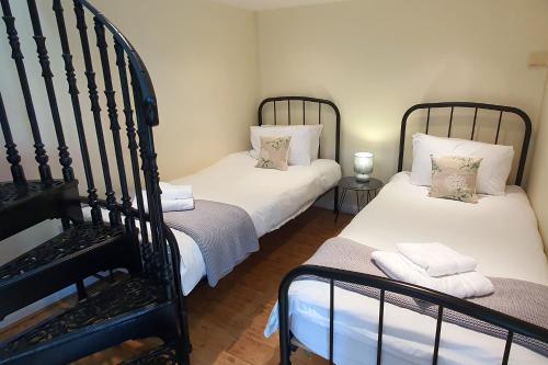 two twin beds in a room with a staircase at Sandy's Barn, Foolow, Dogs Welcome in Foolow