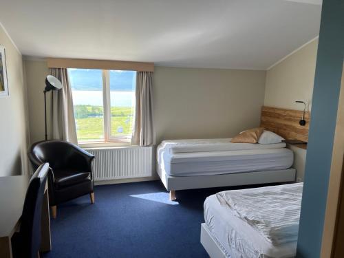 a hotel room with two beds and a chair and a window at Hotel Natur Akureyri in Akureyri