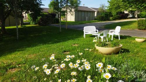 a yard with two chairs and flowers in the grass at Complexe Touristique La Montagne Limousine in Chamberet