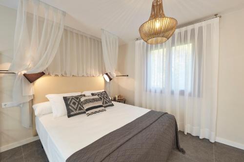 a bedroom with a bed with white curtains and a chandelier at Mirador de Chisten in Gistaín