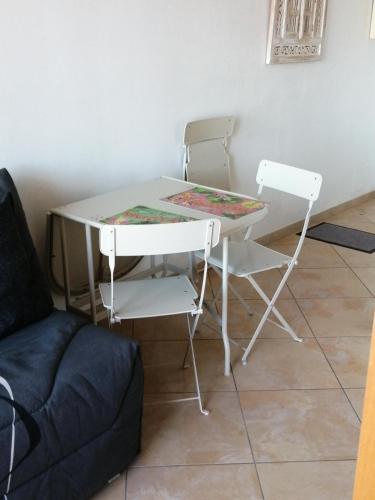 une table blanche, deux chaises et un canapé dans l'établissement Front de mer les pieds dans l'eau, à Carry-le-Rouet