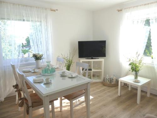 a dining room with a white table and a television at Haus Heimatliebe in Obernheim