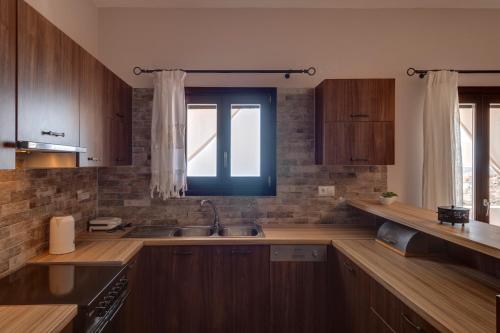 a kitchen with wooden cabinets and a sink and a window at Vera Vista Syros in Ano Syros