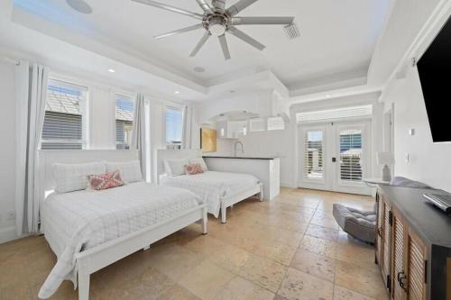 a white bedroom with two beds and a ceiling fan at Seacrest Getaway in Rosemary Beach