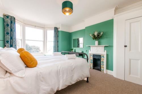 a white bed in a green room with a fireplace at Queen Palm Apartment - Margate - 3 mins walk to beach in Margate