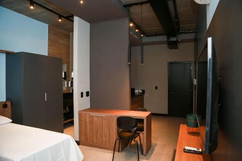 a bedroom with a bed and a desk and a chair at Globo Lar Studios in Limeira