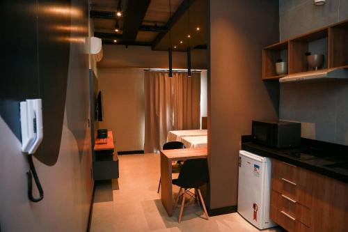 a room with a kitchen with a desk and a bed at Globo Lar Studios in Limeira