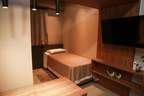 a small room with a bed and a flat screen tv at Globo Lar Studios in Limeira