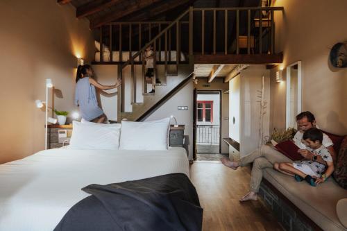 a family sitting on a couch in a bedroom with a large bed at Rouista Tzoumerka Resort in Vourgareli