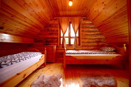 a bedroom with two beds in a log cabin at Milanova koliba Zlatar in Nova Varoš