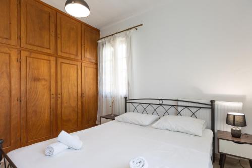 a bedroom with a white bed and wooden cabinets at A&S Seaside House in Lixouri