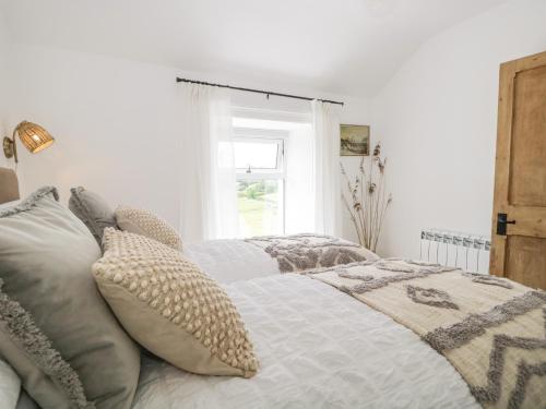 sypialnia z łóżkiem z poduszkami i oknem w obiekcie Sandacre Cottage w mieście Ulverston