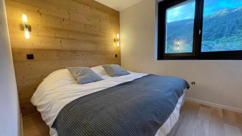 une chambre avec un grand lit avec une fenêtre dans l'établissement Morzine : bel appartement à 5 mn du téléphérique, à Morzine