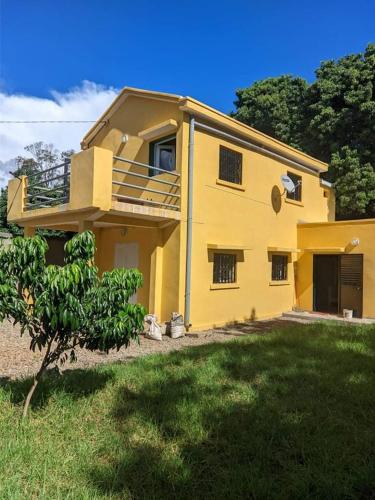 żółty dom z drzewem przed nim w obiekcie Villa Emma Ampefy 
