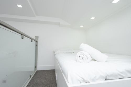 ein Bett in einem weißen Zimmer mit einem Handtuch darauf in der Unterkunft Modern & Stylish Studio in Reading Centre in Reading