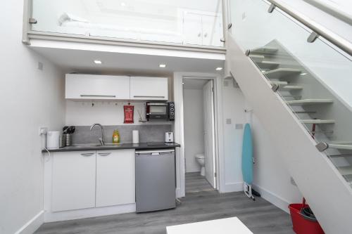 eine Küche mit weißen Schränken und einer Treppe in der Unterkunft Modern & Stylish Studio in Reading Centre in Reading