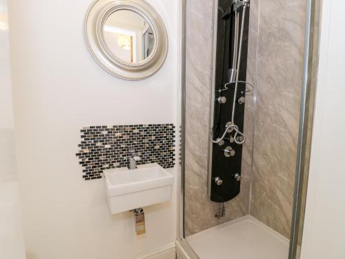 Un baño con ducha con lavabo y espejo. en Gull Cottage, en Bodorgan