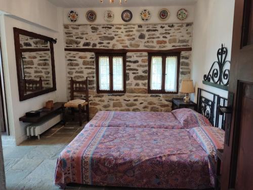 a bedroom with a bed and a stone wall at Lito's dream villa by the sea! in Amaliápoli
