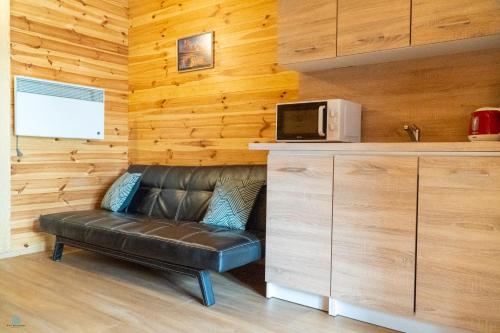 um sofá de couro num quarto com um micro-ondas em Pod Brzozami Apartamenty Domek Ustronny em Ustronie Morskie