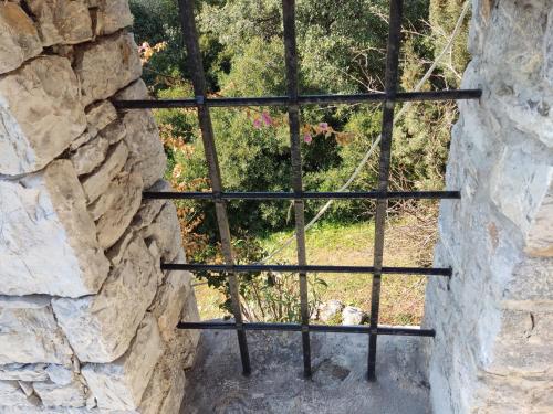 a view through a barred window in a stone wall at Lito's dream villa by the sea! in Amaliápoli