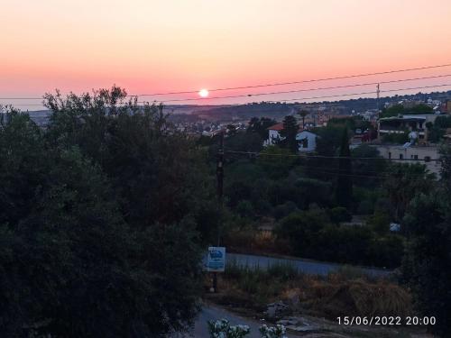 a sunset with the sun setting over a city at Sunset Guest House in Kormakiti