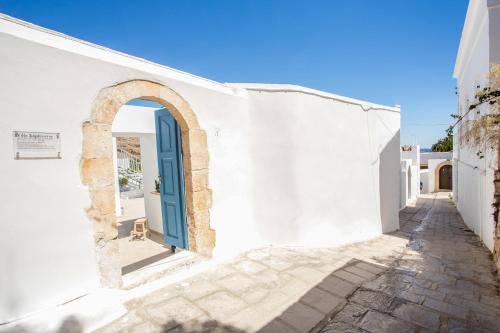 a white building with a blue door on a street at Villa Euphrosyne in Líndos