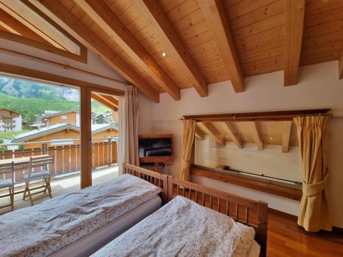 a bedroom with two beds and a large window at Chalet Haus Perla in Saas-Fee