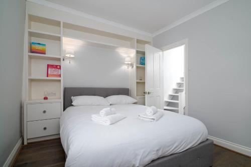 a bedroom with a white bed with two towels on it at GuestReady - Modern Apt in Chelsea with a Terrace in London