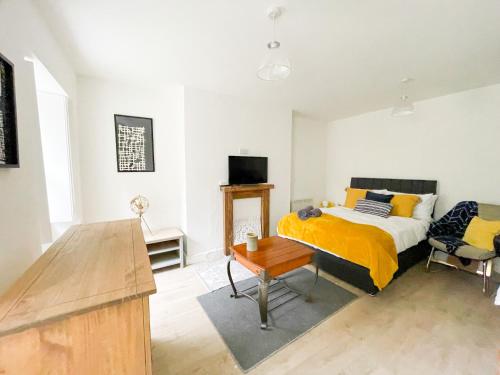 a bedroom with a bed with a yellow blanket at Pittville Studios - By Suitely in Cheltenham