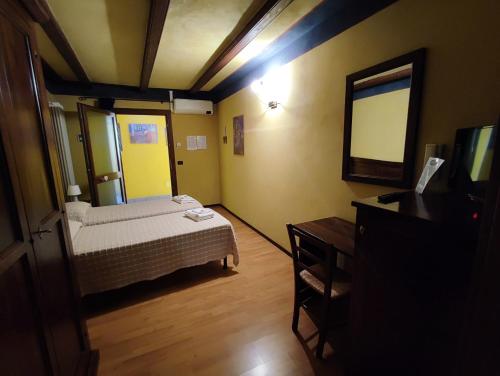 Dormitorio pequeño con cama y espejo en Maison Manu, en Perosa Argentina