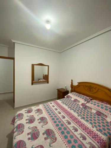 1 dormitorio con cama y espejo en la pared en Alojamiento entero / Los Narejos, en Los Alcázares