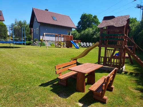een park met een houten picknicktafel en een speeltuin bij Domki u Marka in Polańczyk