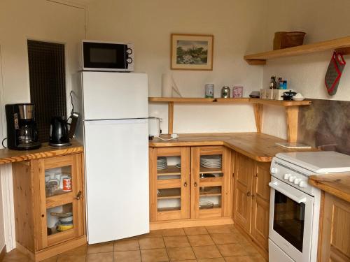 uma cozinha com um frigorífico branco e armários de madeira em Orchidée 1 et 2_ départ de randonnées em Mariac