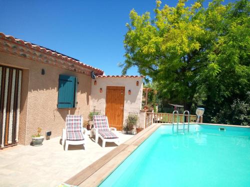 a swimming pool with two chairs and a house at Olive View in Puissalicon