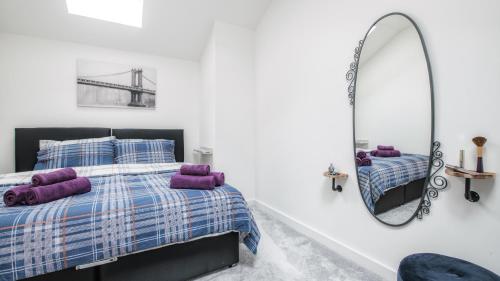 a bedroom with a bed with purple pillows and a mirror at Stunning 2 bed with outside balcony, super king beds and 75’’ TV! in Bradford