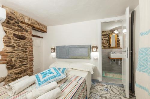 1 dormitorio con cama y pared de piedra en Bed and Terrace Caterina, en Baunei