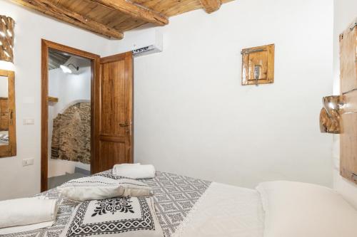 a white bedroom with a bed and a wooden door at Bed and Terrace Caterina in Baunei